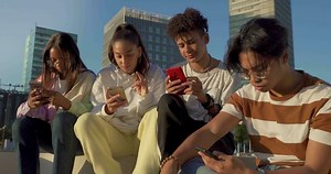 Group of happy teenage friends looking their phones without talking ignoring each other.
