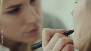 Makeup artist paints lips of a beautiful girl. Model with lipstick. Maroon lipstick. Lipstick wine-colored on model s lips. Make-up artist using lipstick brush. Trendy shades of lipstick