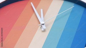 4K footage Time lapse Close-up zoom in Rainbow-colored wall clock spins to tell the time.