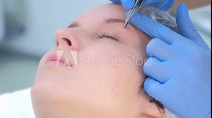 Cosmetologist plucks out hair on eyebrows with tweezers for woman, face closeup. Eyebrows tweezing procedure. Beautician is making brows correction with cosmetic tweezer. Beauty industry.