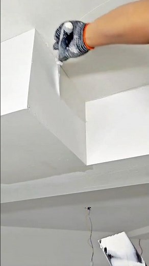A professional is smoothly finishing ceiling drywall corners using joint compound