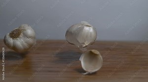 Cloves of garlic falling in slow motion onto a cutting board, moving shot