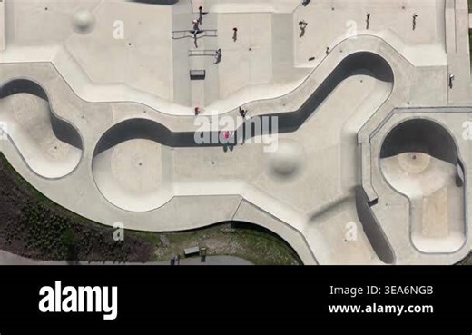 High angle aerial footage showing young people skateboarding and performing tricks in a modern concrete skatepark, enjoying an active urban lifestyle and outdoor recreational sport on a sunny day Stock Video Footage - Alamy