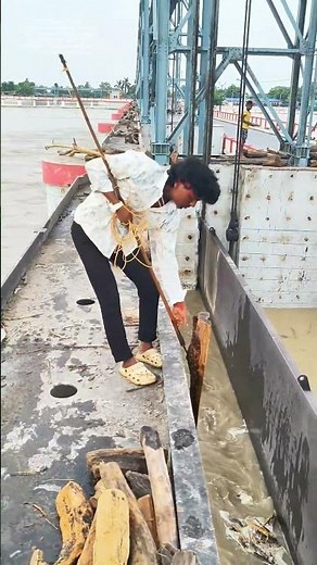 Wie ein langer Holzhaken und ein Seil angeschwemmte Stämme aus dem Hochwasser ziehen