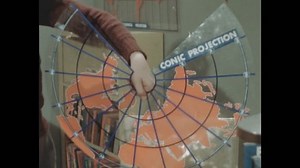 1940s: Boy removes plastic cone from globe top and holds it up. Map on unfolded plastic cone is labelled Conic Projection.