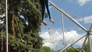 A lady jumping on a trampoline with harness as a safety gear for the activity