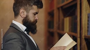 Concentrated professor. Bearded man in classic suit read book in library. Classic literature. Man reading book in bookshelf. English classic mood. Man picking a book in a library. Stock Video