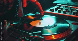 Deejay spinning vinyl musical record on turntable, playing disco during dj rave, close-up. Nightlife and music