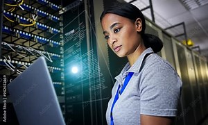 cyber security specialist holding laptop computer, typing, standing in green-lighted server room,