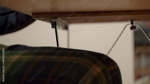 Working at home at a laptop in funny socks and pajamas. A man is typing on a keyboard at a desk in home clothes. Remote study or work concept.