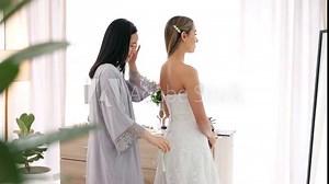 Happy bride in wedding dress, friends helping with knot on luxury corset back string and young women together in home. Asian woman hug supporting friend, marriage ready and bridesmaid happiness