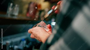 The bartender breaks the ice Close-up of male hands cracking ice with a sharp tool in a bar