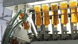 Filling line for production of alcoholic beverages. Glass bottles in distillery production line in Factory for bottling alcoholic beverages. Spill of brendy, whiskey in glass bottles at distillery.