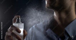 Anonymous man spraying luxury fragrance in extreme slow motion with scent particles to wet skin after dressing . concept of men's perfume and aftershave sensual men. Man perfumed after shave