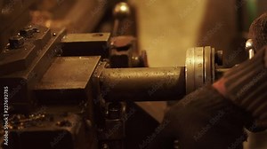 Working process at the machine at engineering plant. The man the worker at the machine adjusts the device. Stage of machine-building production.