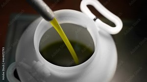 Closeup of an extra virgin olive oil production line. Clean organic olive oil is poured into a while plastic drum. Oil mill.