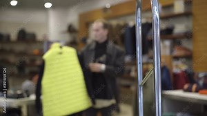 Shoplifting scanner at shop entrance with blurred man choosing clothes at the background. Male Caucasian thief taking goods and running away from store. Crime and security concept.