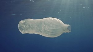 La bouteille de plastique dérive sous la surface de l'eau sous les rayons du soleil. Ralenti, une bouteille en plastique jetée dans la mer dérive lentement dans la colonne d'eau sous les rayons du soleil matinal. Pollution des océans