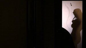 Silhouette of a woman changing clothes behind a glass door. She takes off her underwear