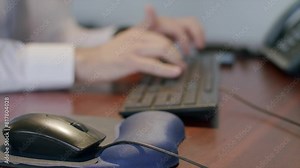 Closeup footage of adult male hands using the keyboard to type on a wooden brown desk