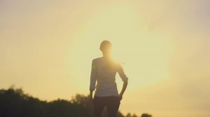 Woman walking away from the camera on a summer meadow on sunset. Slow motion 240 fps. HD 1920X1080.