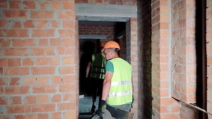 Interior decoration works of painters and plasterers at construction sites. Workers move between rooms with cement solution