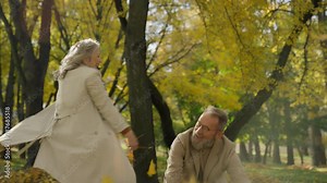 Happy family old couple funny hilarious crazy two grandparents retired woman man cheerful throwing leaves in autumn forest enjoying romantic date elegant aged husband wife having fun spinning outdoors Stock Video