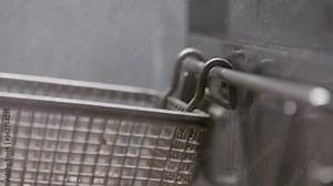 Deep frying a basket of fresh-cut french fries. Professional kitchen deep fryer. Shot in 4k