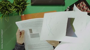 Top down shot of man trying to find contract among papers with diagrams and graphs