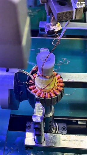 Winding copper coils onto stator core with guide fixture.