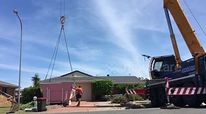 Crane lifts new pool over house and into position