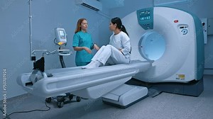 Radiologist with patient in room of computed tomography. Neurologist doctor standing near patient and explaining procedure. Medical worker talking, patient listening to doctor carefully.