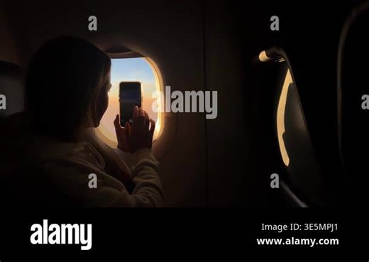 Silhouetted female passenger taking a photo of the sunset sky from the airplane window Stock Video Footage - Alamy