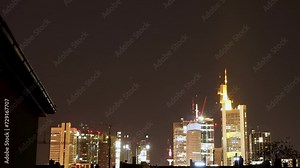 Nighttime view of Frankfurt skyline with illuminated buildings under a starry sky, timelapse