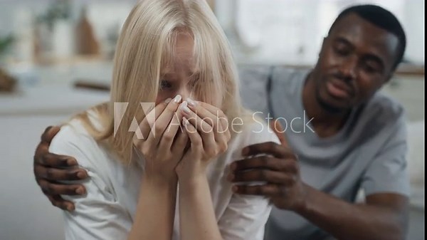 Blonde woman crying when quarreling with husband, black man hugging his wife. Interracial marriage, loving couple swearing in apartment, diversity and unity of people, different races and culture