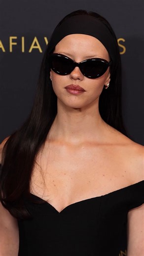 Stealth sleekness. Mia Goth wore Calvin Klein Collection to the AFI Awards Luncheon. Seen in a black off-the-shoulder cocktail dress with a sweetheart neckline. | Calvin Klein