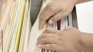 Close-up hand of businesswoman searching for financial and accounting file paperwork in an office file cabinet