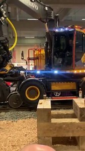 An excavator operator showcased the capabilities of a large machine by carefully pouring an energy drink into a glass. Once the glass was full, the operator picked it up using the machine's claws and handed it over to a man in the audience. | Jukin Copyright Management