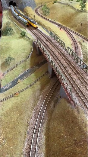 A passenger train crossing a bridge on an N gauge railway.