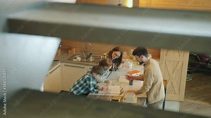 High angle view of smart kids doing homework and caring parents mom and dad helping with studies around table in kitchen. Education and family concept.
