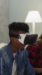 Attractive women sports fans and black guy with VR headset enjoy baseball game in apartment closeup slow motion. Virtual reality for amusement and rest