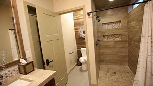 Modern Master Bathroom Pan from Sink to Shower. camera moves from modern bathroom sink to show toilet room and stand up shower. Second shot is lowering close up of shower