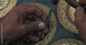 A master embosser creates a pattern on a copper plate using ancient technologies.
