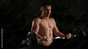 Handsome man with big muscles, posing in the gym muscular man lifting weights over dark background muscular man working out in gym doing exercises with barbell at biceps strong male. close-up