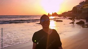 Young Indian woman walking on the Goa beach against the setting sun background. Indian female tourist walks along the beach at sunset.
