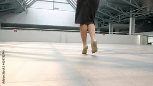 Close-up of the feet of a business woman in elegant shoes walking down the lobby of a business center. A successful career as an independent woman in a corporation. bottom rear view