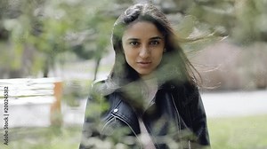 Pretty brunette woman in a park walking between tree branches