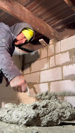 Filling all voids with mortar cement before we parge the block foundation wall with Portland cement