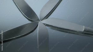 Five scalpels fanned out rotating counterclockwise on a glass mirror. HD 1080.