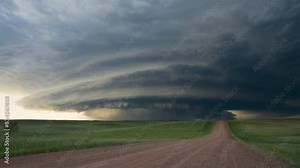 dramatic time-lapse of a supercell thunderstorm forming over a rural landscape, showcasing the dynamic movement of clouds and changing light conditions